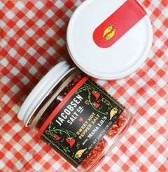 Two jars of Jacobsen Sweet Hot Pepper Salt on a white and red checkered tablecloth. 